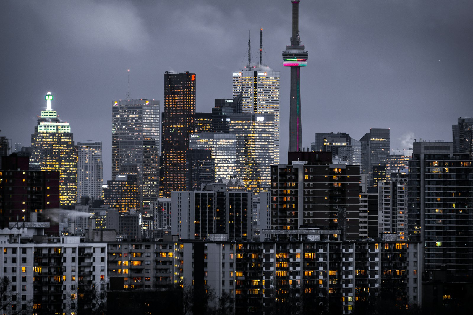 A city skyline at dusk with illuminated towers and a broadcast tower