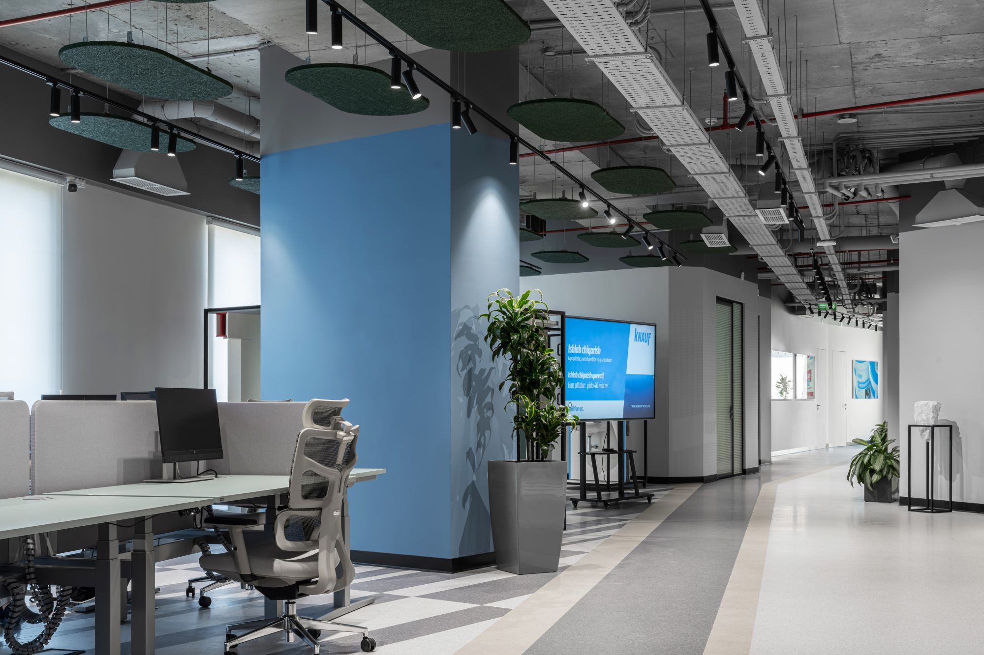 An open office floor with long desks where dozens of people work at laptops.