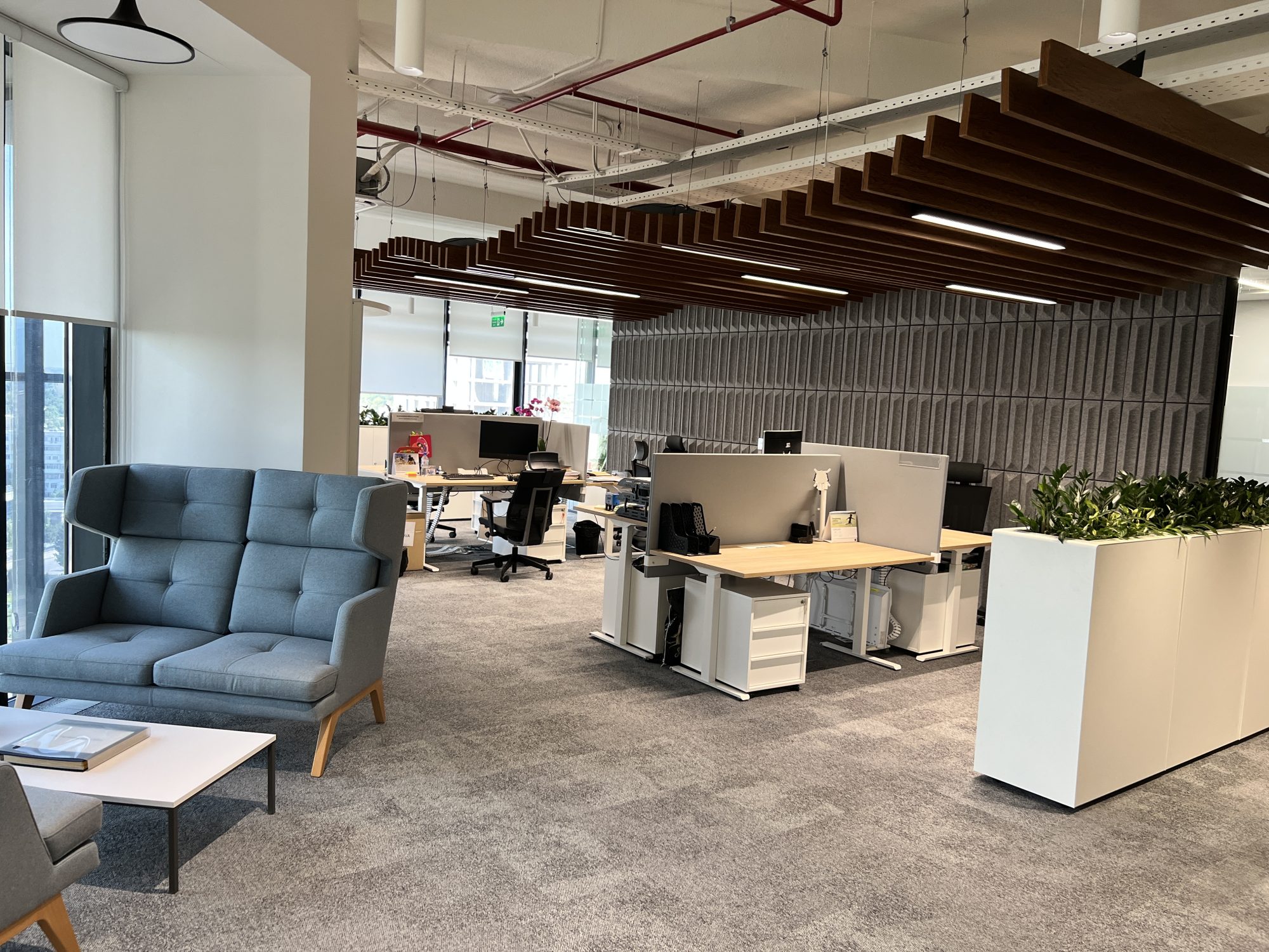 A meeting room with a rough wooden table, white chairs and a floor to ceiling window overlooking the city.