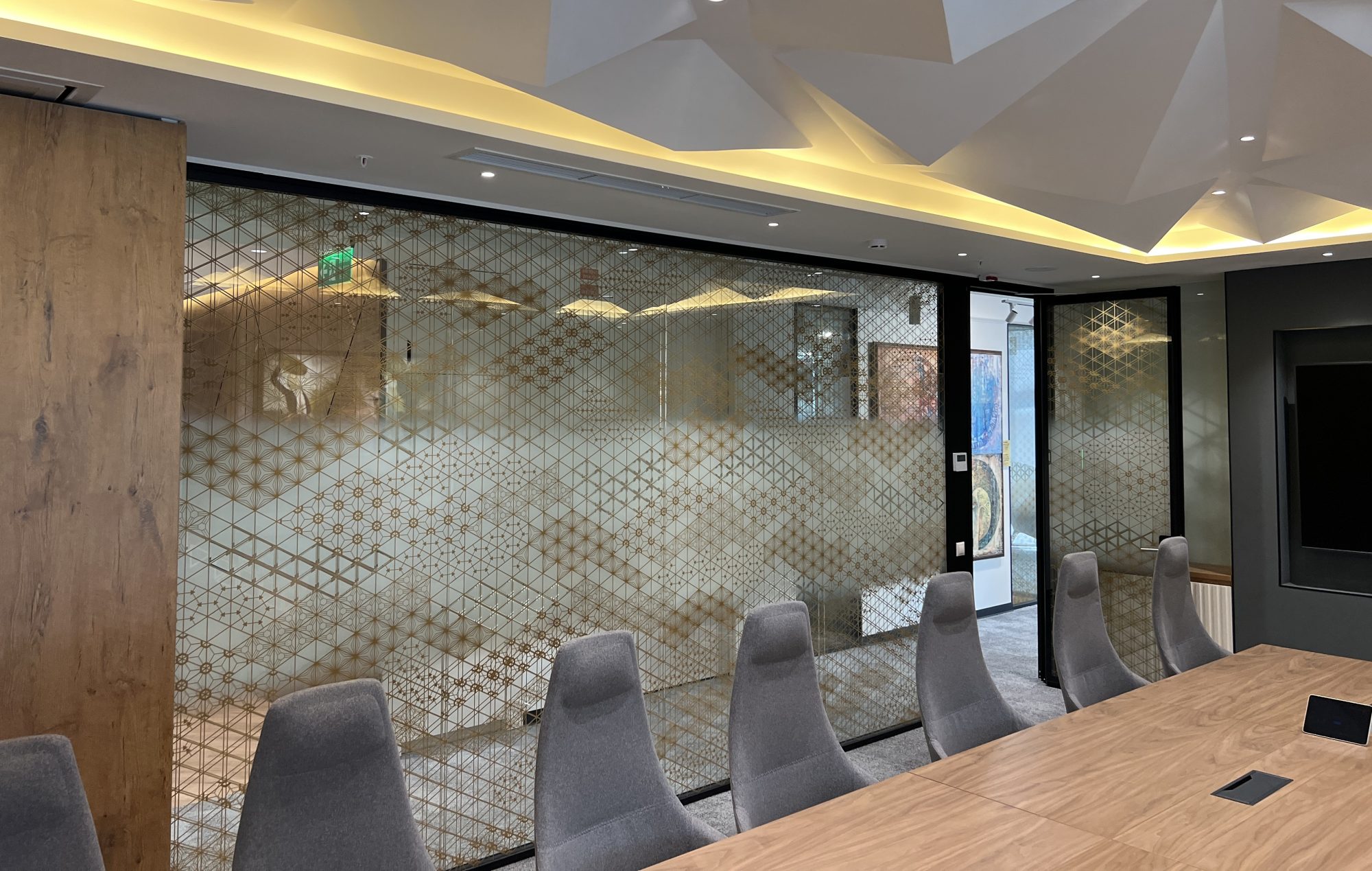 A loft style meeting room with an exposed concrete ceiling, open ductwork, a wood table and pink upholstered chairs.