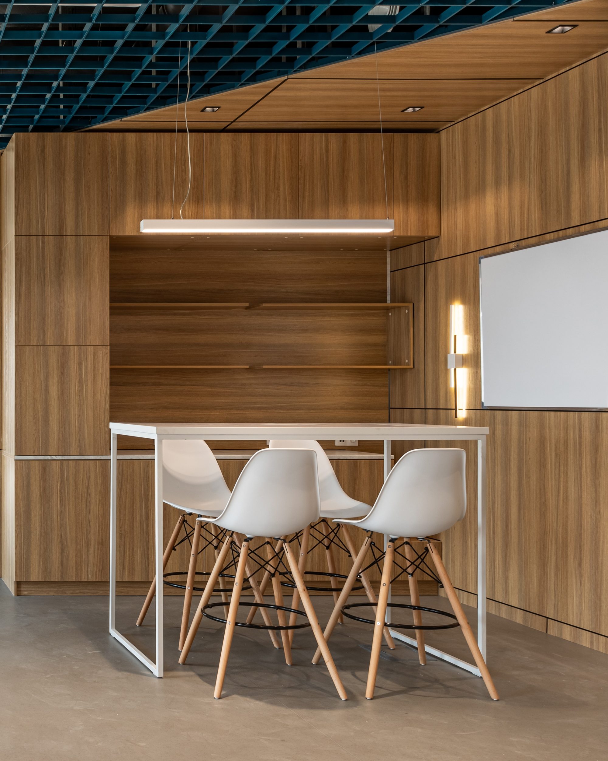 A meeting room with a rough wooden table, white chairs and a floor to ceiling window overlooking the city.