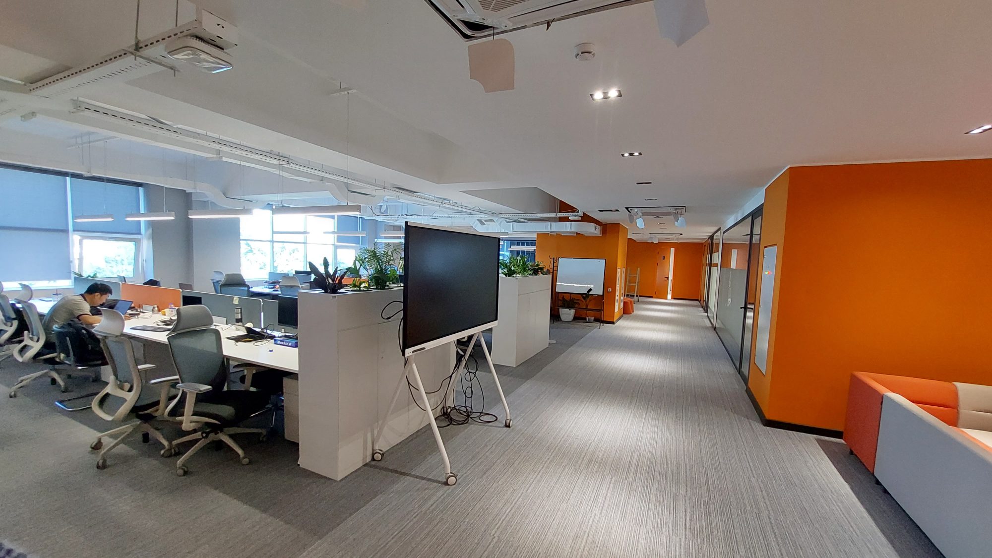 A meeting room with a rough wooden table, white chairs and a floor to ceiling window overlooking the city.
