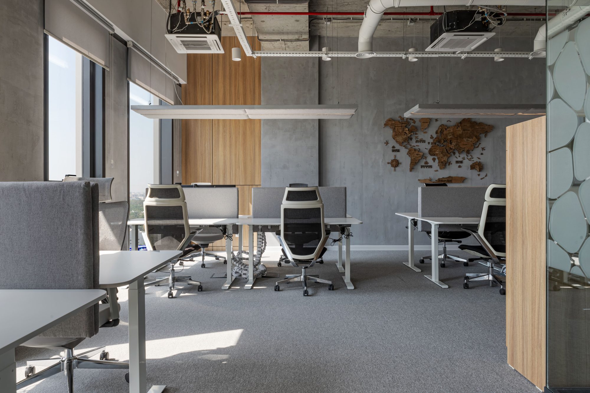 A loft style meeting room with an exposed concrete ceiling, open ductwork, a wood table and pink upholstered chairs.