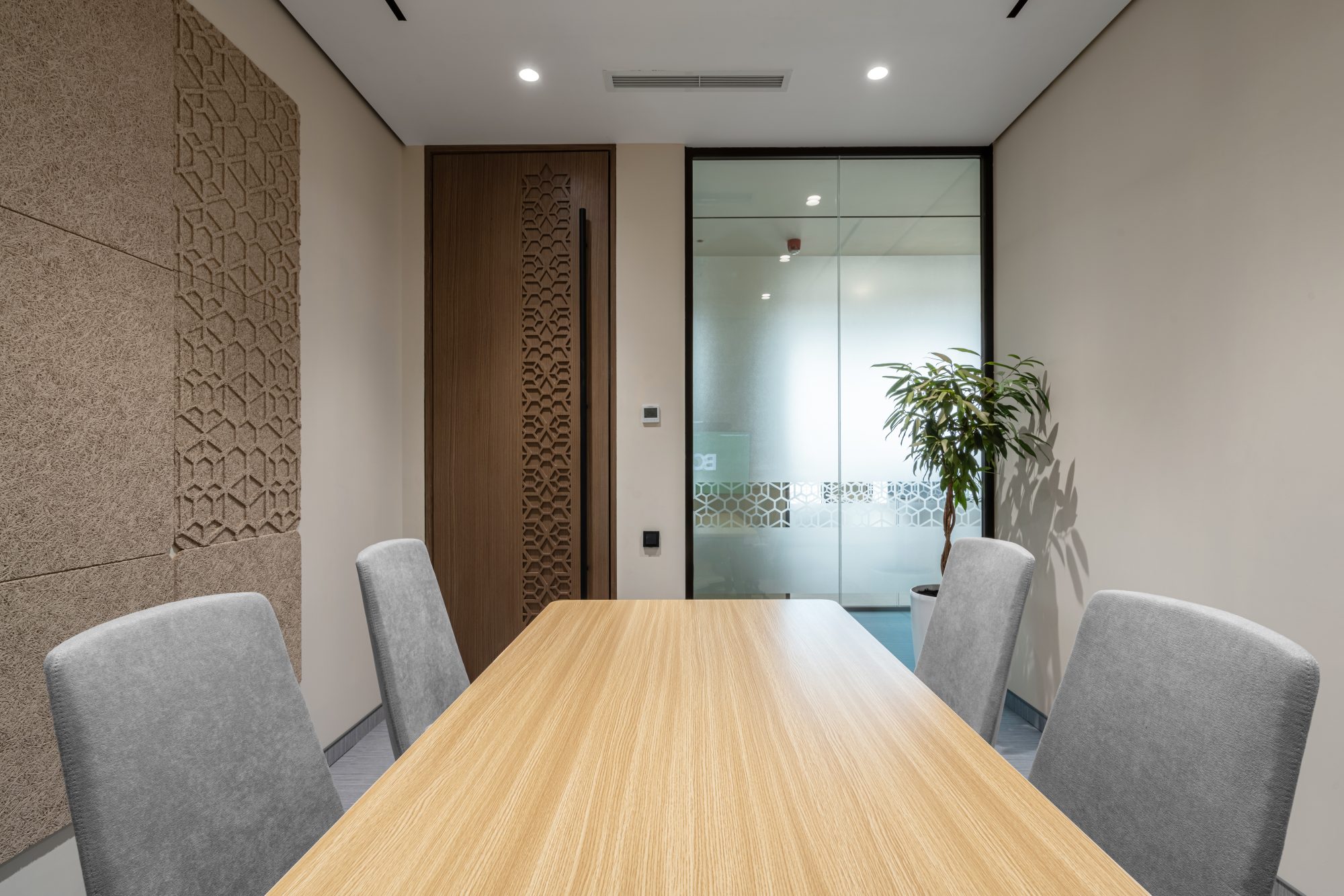 A loft style meeting room with an exposed concrete ceiling, open ductwork, a wood table and pink upholstered chairs.