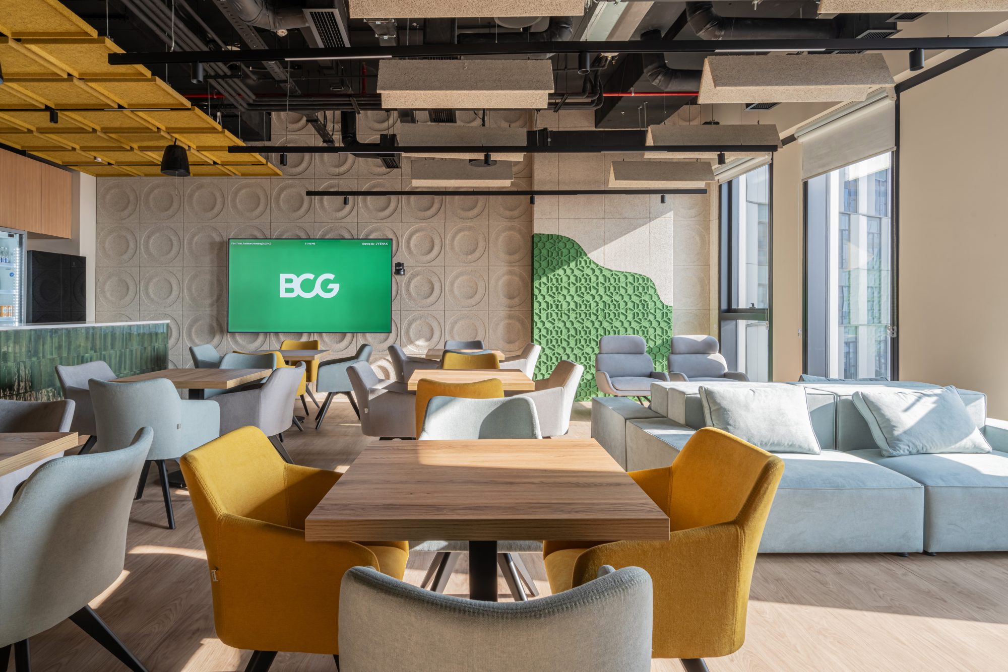 A break out area with a long armed floor lamp, grey and green armchairs and a sofa.