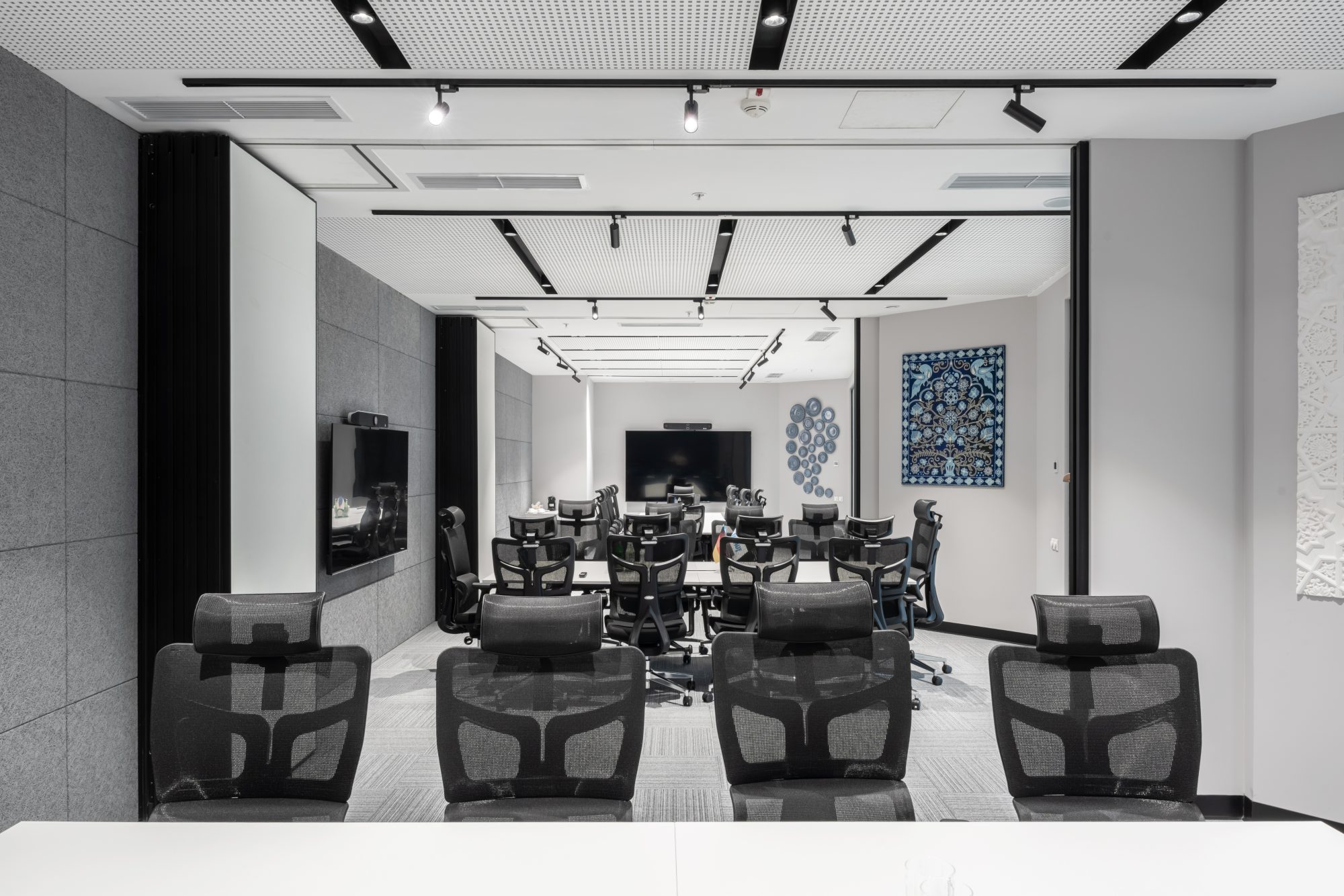 A loft style meeting room with an exposed concrete ceiling, open ductwork, a wood table and pink upholstered chairs.