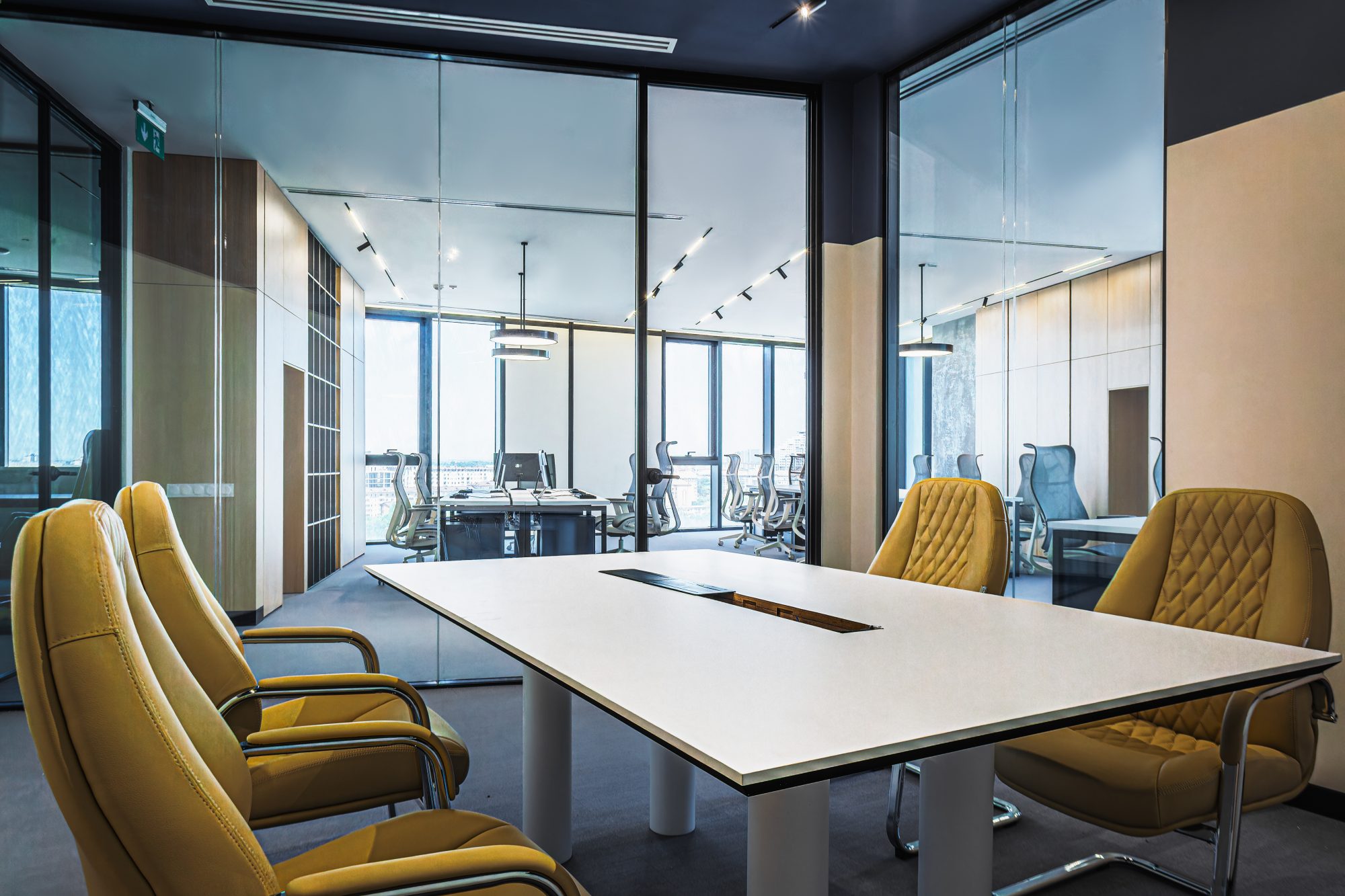 An empty break out area with a bench, low shelving and a kitchenette beside a glass walled corridor.